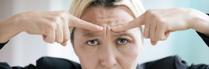 A stressed, frowning middle-aged Caucasian businesswoman knitting her brow with a stressful and...