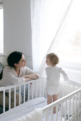 mom puts the baby to sleep by rocking him, mom holds the baby in her arms gently hugging and kissing him, mother and child, healthy sleep of the child with the mother.