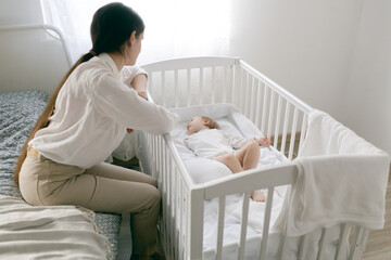 mom puts the baby to sleep by rocking him, mom holds the baby in her arms gently hugging and kissing him, mother and child, healthy sleep of the child with the mother.