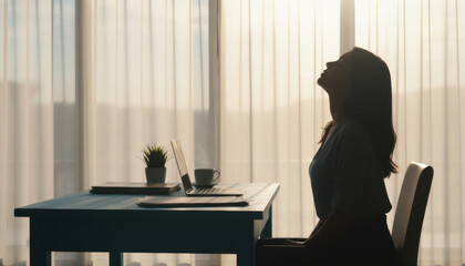 Woman sits at desk, enjoying moment of tranquility by window with soft light