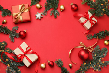 Frame of fir tree branches, gifts and Christmas decor on red background, flat lay. Space for text