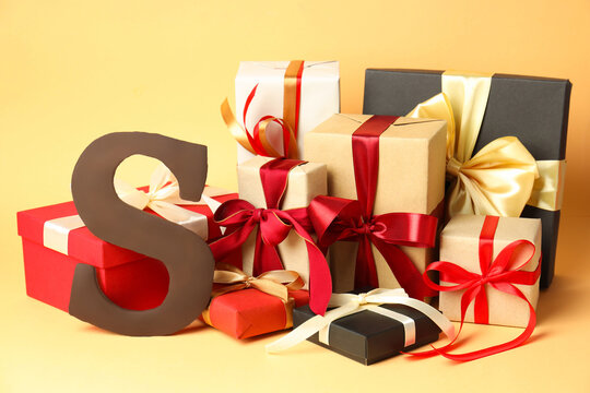 Sinterklaas (Saint Nicholas) Day. Chocolate letter S and gifts on beige background, closeup - Powered by Adobe