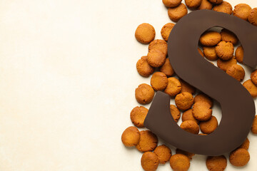 Sinterklaas (Saint Nicholas) Day. Chocolate letter S and kruidnoten cookies on light background,...