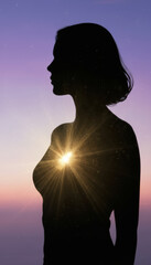 Silhouette of woman with glowing heart, set against colorful sunset sky, evokes sense of warmth