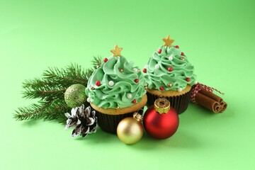 Christmas tree shaped cupcakes, cinnamon and festive decor on green background, closeup