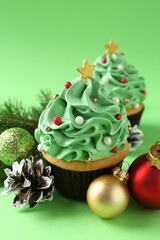 Christmas tree shaped cupcakes and festive decor on green background, closeup