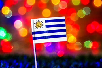 The Uruguay flag shines against a vibrant, abstract rainbow bokeh background. Ideal for national events, South American pride, soccer, or festive celebrations.
