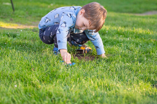 Junge spielt mit Auto auf einer Wiese