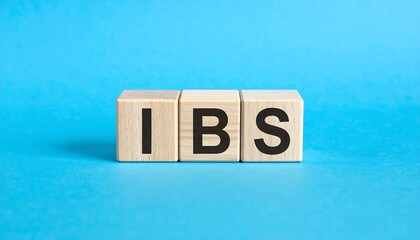 Three wooden blocks spell the abbreviation "IBS" in black letters on a vibrant, solid blue background. The composition suggests medical or health-related topics