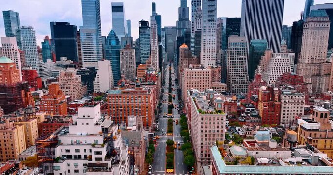 Flight above the wide-lane street of Big Apple with multiple yellow taxi. Approaching the high-rise buildings in the downtown of New York, USA.
