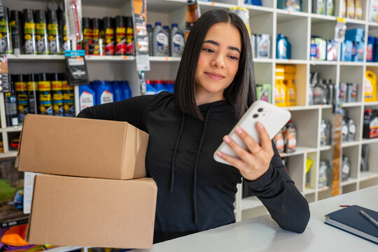 Young woman checking online orders and preparing packages for shipping
