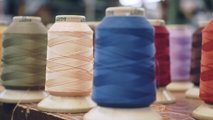 Closeup of colorful spools of thread neatly arranged in a row showcasing various vibrant hues of sewing material for textile and craft projects.