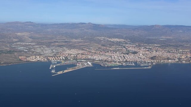 Aerial left side view of Alicante city center and harbor, taking from a plane cokpit in a sunny day. Handheld camer shot from cokcpit.