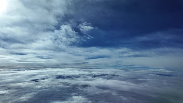 POV flying peacefully through multilayered fluffy. stratus clouds, with a faded sun above in the left frame corner. Aerial footge taken from a plane cokpit.