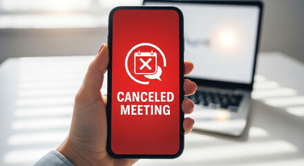 Canceled meeting icon on app displayed on smartphone in office setting, remote work and technology disruption