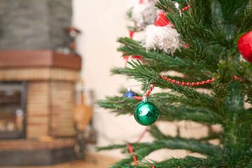 Christmas home scene with a plastic fir tree decorated with the first ornaments beside the fireplace