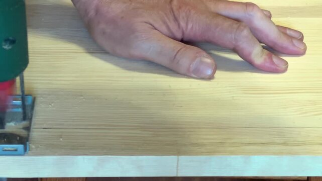 Sawing of wooden plank with jigsaw along the marking line