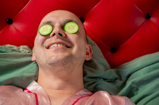 Cucumber slices on the face of a short-haired man, skincare and relaxation concept