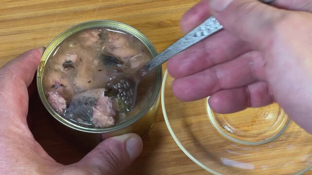 Laying out canned fish slices from tin to glass saucer
