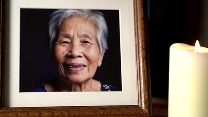 A somber tribute featuring a framed photo illuminated by candlelight, evoking memories and warmth.