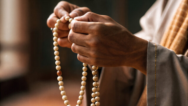 Fingers sort through prayer beads in a mantra. Prayer with the help of prayer beads