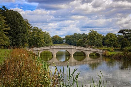 The five arch bridge and its reflection across the serpentine lake at Painshill Park in Cobham Surrey England UK