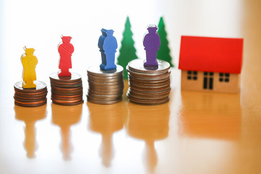 遺産相続、財産分与のイメージ、分けて積まれた硬貨の上に立つ人の人形と家、法定相続人とお金のイメージ