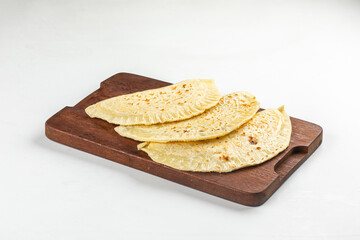 Traditional Azerbaijani qutab flatbreads with herb filling served on wooden board over white background