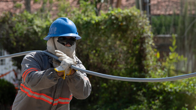 Retrato de trabalhador da constru&ccedil;&atilde;o civil com balaclava, &oacute;culos escuros e equipamentos de seguran&ccedil;a trabalhando em manuten&ccedil;&atilde;o de rede de alta tens&atilde;o