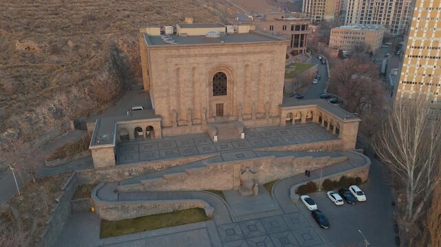 Aerial view of the Matenadaran in Yerevan, Armenia &mdash; iconic stone building with statues of Armenian scholars, located on a hill with the cityscape and surrounding mountains in the background. 