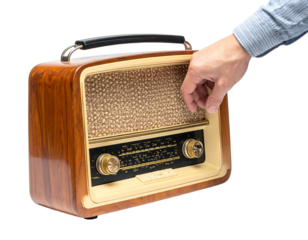A person's hand turns the dial on a vintage, wooden radio. The device has a speaker grille and controls