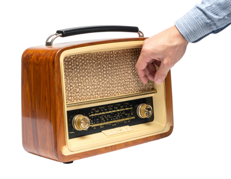 A person's hand turns the dial on a vintage, wooden radio. The device has a speaker grille and controls