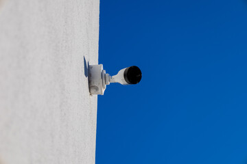 A CCTV camera is securely mounted on a wall, focused towards the open sky, ensuring constant monitoring and security for the surrounding area