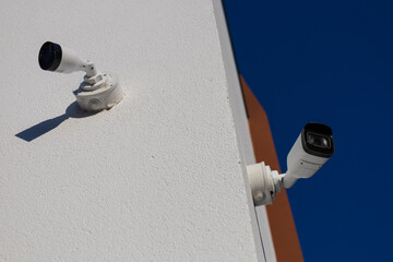 Two surveillance cameras are mounted on the wall of a building, providing security and monitoring capability for safety purposes