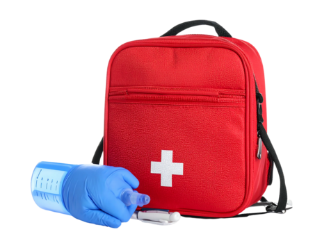 A red first aid bag with a white cross sits upright. Next to it, a gloved hand holds a blue medical device