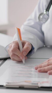 A healthcare professional in a lab coat is completing patient documentation on a clipboard while using a laptop for digital records, showcasing the blend of traditional and modern medicine.