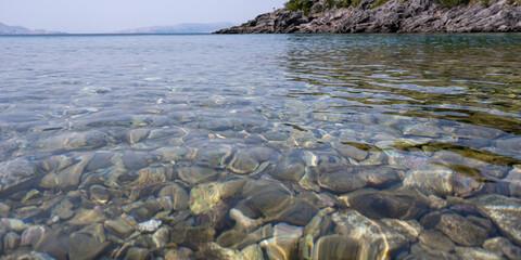 View of stones in the  water at the seashore with island in the background