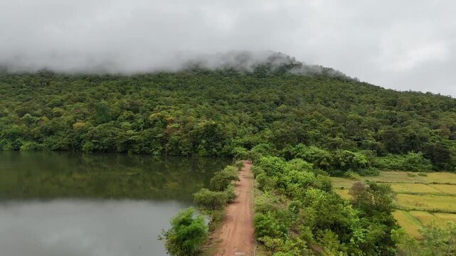 Stunning 4K aerial view of Ban Na Phang reservoir in Sakon Nakhon, Thailand, shrouded in morning mist with serene water and lush surrounding landscape.