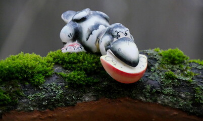 A toy crow and cheese on a stump in an autumn forest on a cloudy day.