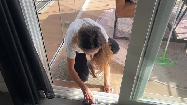 Mujer limpiando los ra&iacute;les de la puerta corredera, Cuidado del hogar