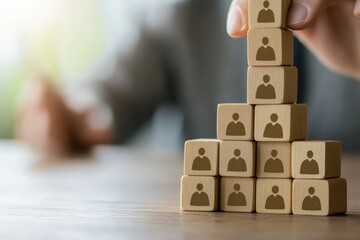 Team Structure and Hierarchy: A hand meticulously arranges wooden blocks etched with person icons, symbolizing organizational structure and the concept of a growing team.