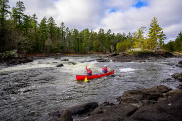 Success: two young women at the bottom of a rapid on the Madawaska River with dramatic white water trees and sky in the background room for text