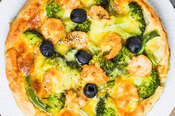 Delicious broccoli shrimp pizza with olives and melted cheese