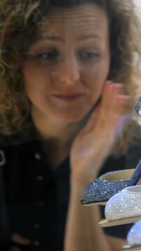 Emotional young woman looking at luxury glitter high heels in a shop window, dreaming of buying them. Her face reflects desire, longing, sadness, and the temptation of consumerism