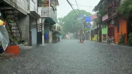 Children playing in a completely flooded street during heavy rain. Extreme weather events caused by climate change.
- Powered by Adobe