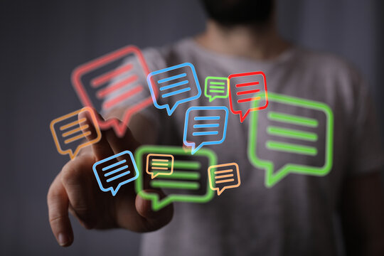 A modern communication concept with speech bubbles floating around a hand reaching out to touch a futuristic digital network interface. - Powered by Adobe