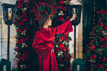A serene holiday scene featuring a woman in a luxurious red satin dress sitting thoughtfully beside...