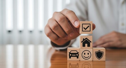 Hand stacking wooden blocks with insurance icons for car home and health protection