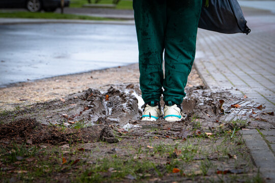 Person Standing in Muddy Puddle After Rain — Dirty Sneakers and Wet Ground Symbolizing Autumn Weather and Real Life Moments