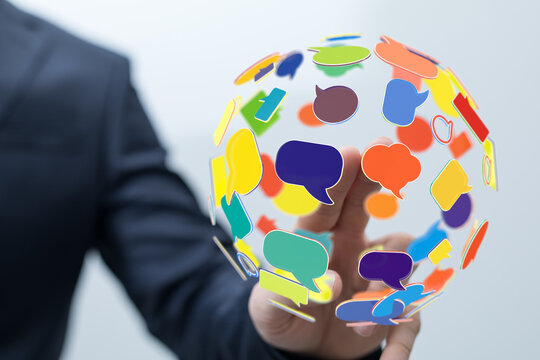 Concept image of a man in a suit holding a globe of speech bubbles, representing global communication, social media, and online interaction. - Powered by Adobe